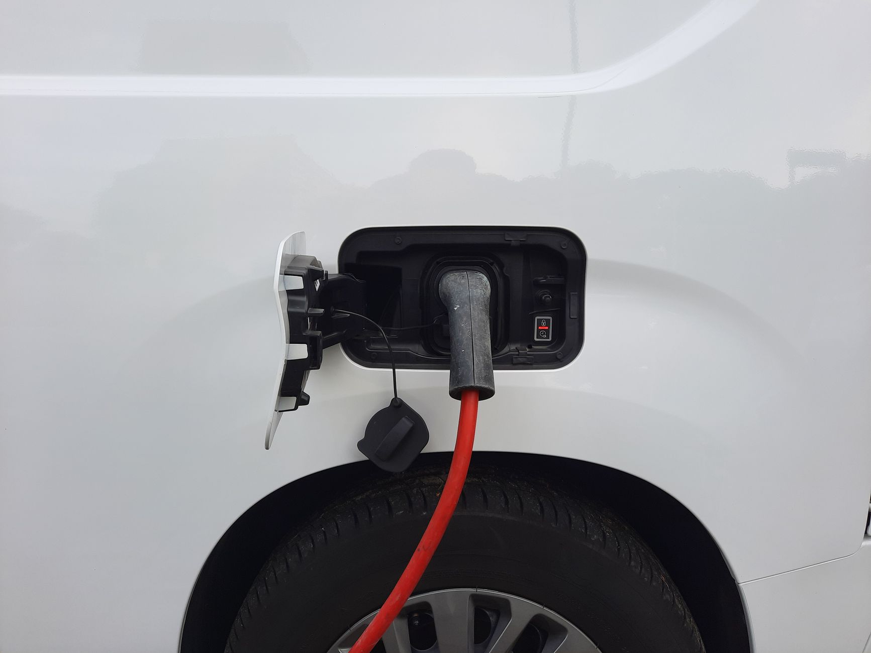 Câble de recharge branché sur la prise d'un véhicule blanc